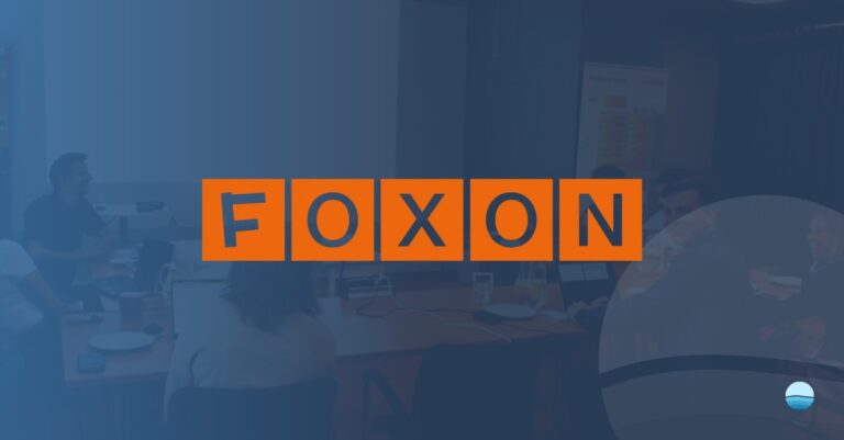 Orangefarbene Blöcke mit dem Wort „FOXON“ in fetten blauen Buchstaben überlagern eine verschwommene Büroszene mit Menschen, die an Schreibtischen arbeiten, und unterstreichen damit die Kompetenz des Unternehmens im Bereich i-flow-Lösungen; in der Ecke ist ein kreisförmiges Logo zu sehen.